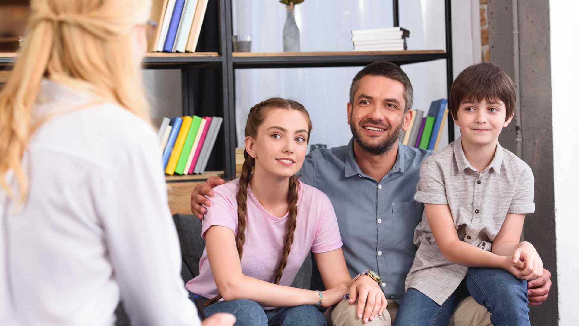 Eine Familie sitzt gemeinsam auf einem Sofa in einem Beratungsgespräch.