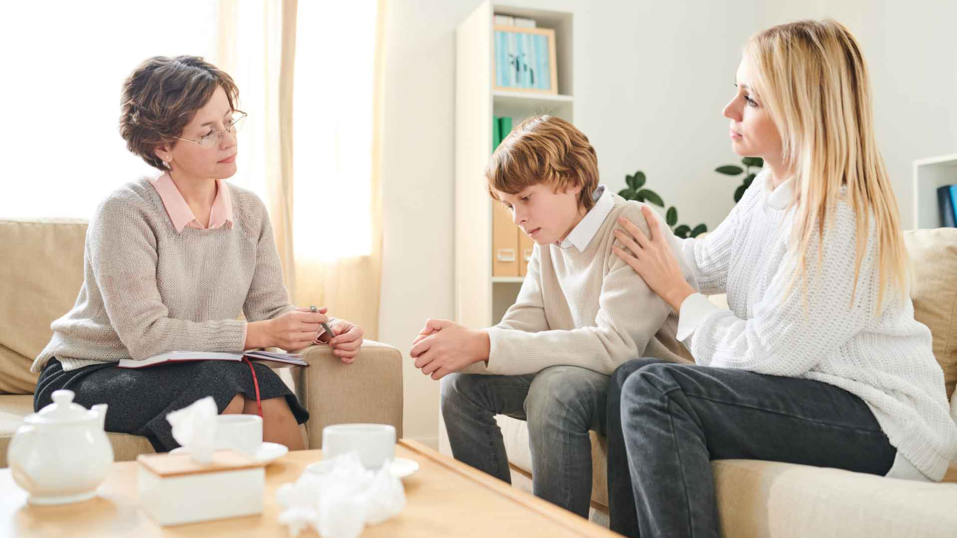 Zwei Erwachsene und ein Jugendlicher sitzen gemeinsam in einem Beratungsgespräch