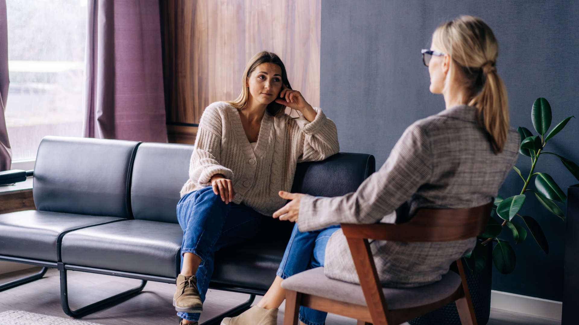 Zwei Frauen sitzen sich gegenüber in einem Wohnraum und führen ein Gespräch.