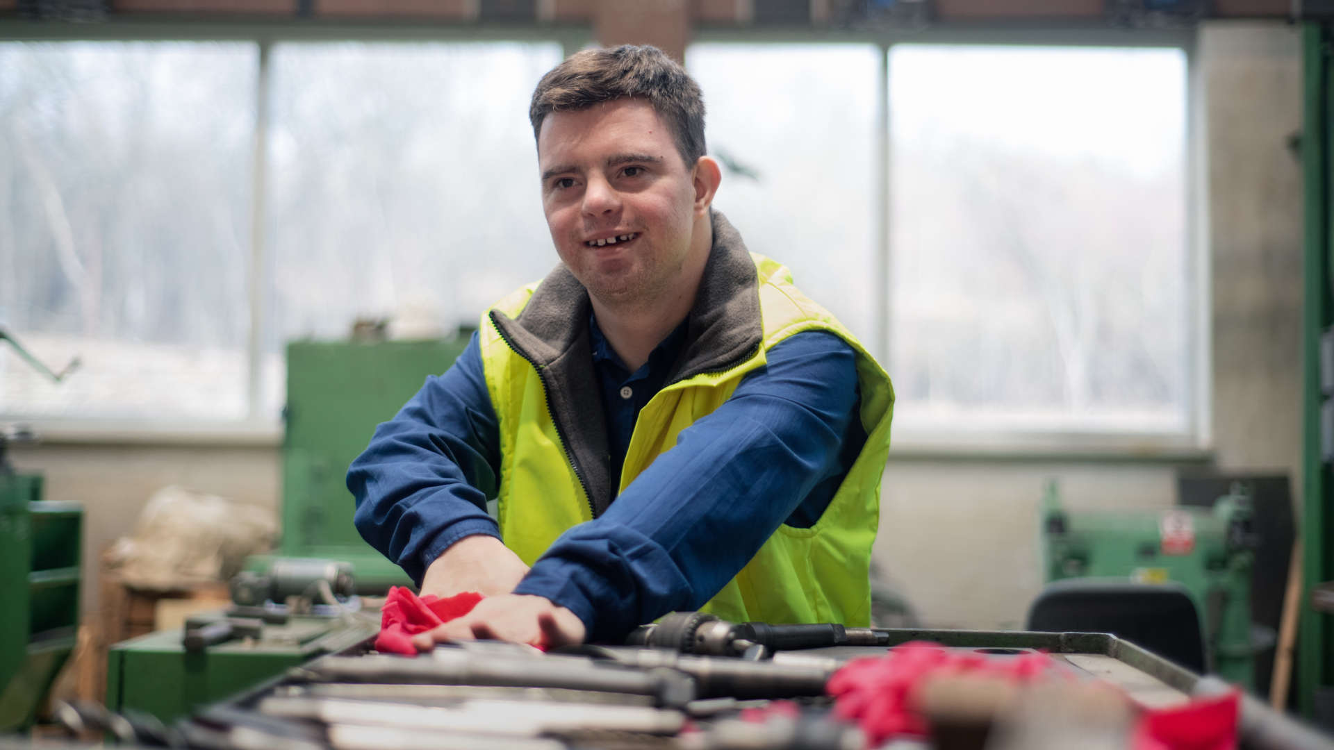 in Mann arbeitet konzentriert an einem Arbeitsplatz in einer Werkhalle.