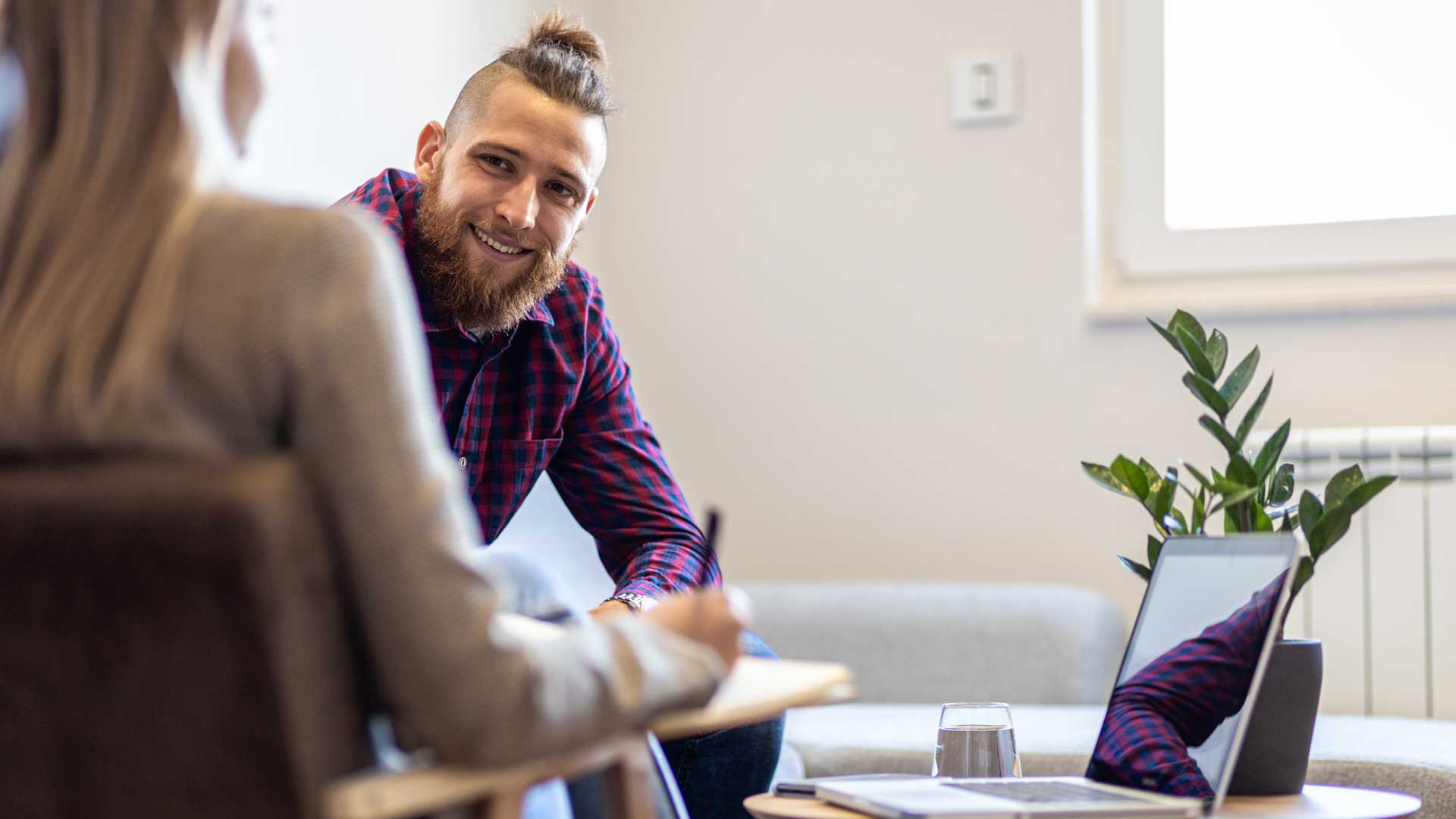 Zwei Erwachsene sitzen sich in einem Beratungssetting gegenüber und sprechen miteinander.