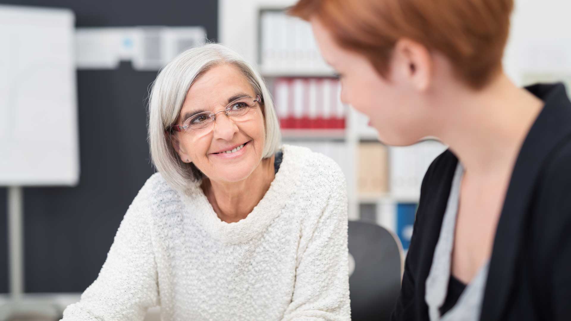 Gesprächssituation zwischen zwei Frauen in ruhiger Arbeitsatmosphäre.